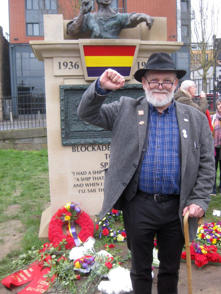 Sculptor Frank Casey stands in front of the monument 'Blockade-Runners to Spain' his fist raised in solidarity – part of a photo reportage of the unveiling of the monument 'Blockade-Runners to Spain' in Glasgow, 2. March 2019