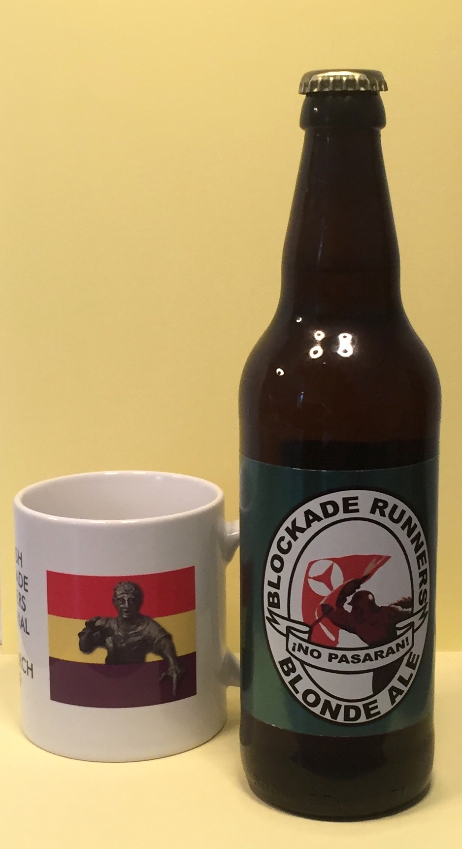 Mug and beer bottle with motifs of respectively the top bronze sculpture of the monument by sculptor Frank Casey (on a background of the Spanish republican flag) and an illustration of blockade runners with the slogan from the Spanish Civil War "¡No pasarán!" ("They shall not pass") – part of a photo reportage of the unveiling of the monument 'Blockade-Runners to Spain' in Glasgow, 2. March 2019