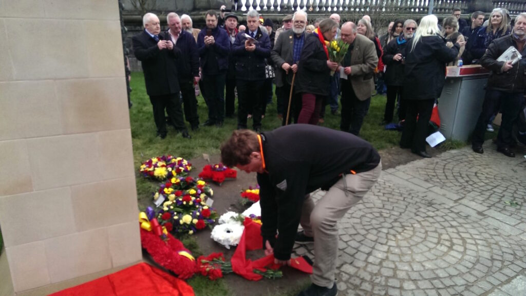 Allan lægger blomster ved monumentet 'Blockade-Runners to Spain' – del af en fotoreportage af afsløringen af monumentet ‘Blockade-Runners to Spain’ i Glasgow 2. marts 2019